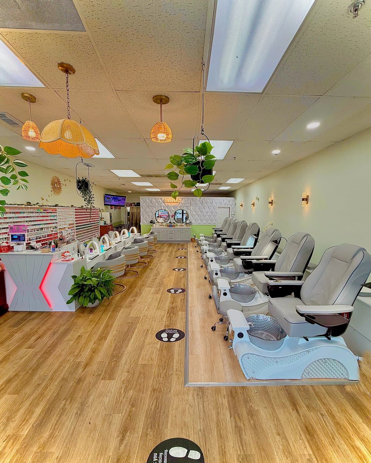 Inside Aloha Nail Salon — a row of pedicure chairs along a wood floor, with the polish wall and front desk at the far end.